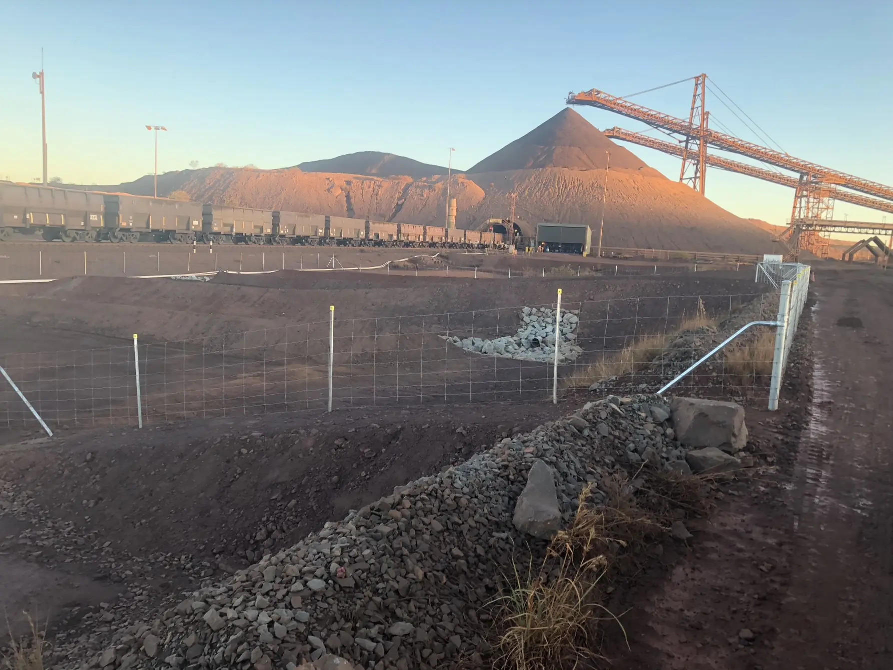 A construction site with a huge mountain of land in the background