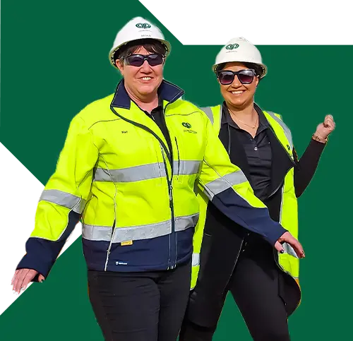 2 lady contractors wearing a helmet and smiling at the camera